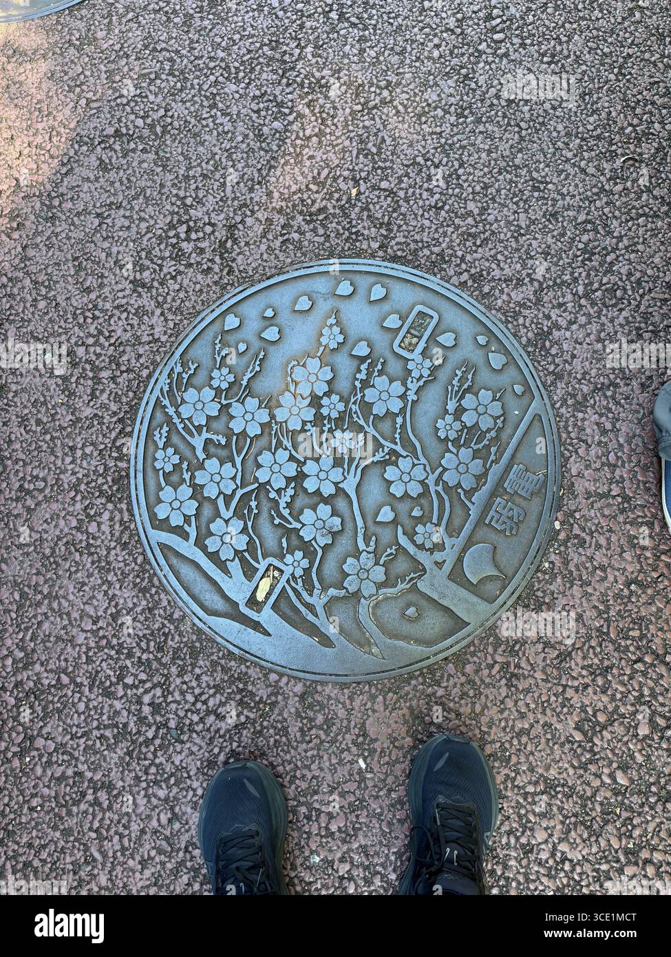 Kirschblüten-Mannloch-Abdeckung auf dem Bürgersteig in Tokio Japan Stockfoto