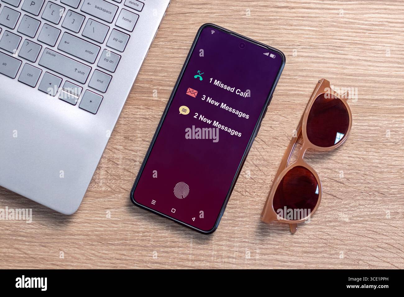 Ein Smartphone auf einem Schreibtisch mit Benachrichtigung über entgangenen Anruf und neue Nachricht auf dem Telefonbildschirm Stockfoto
