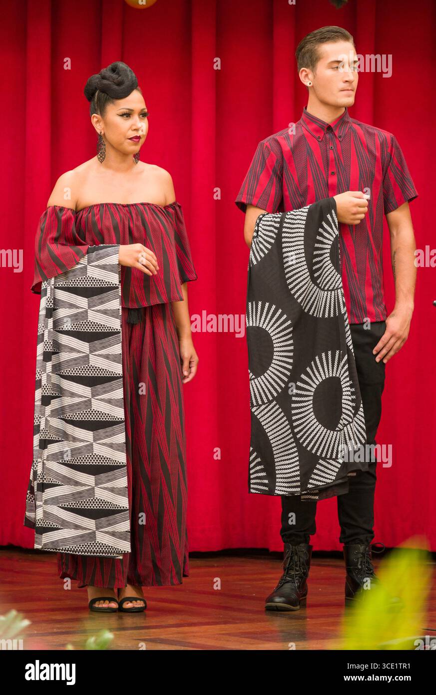 Weibliche und männliche Modelle halten Sie die neue Drucke durch MANAOLA Hawaii auf der Ala Moana Centerstage während des MANAOLA Hawaii Herbst fashion show, Honolulu, Oa Stockfoto