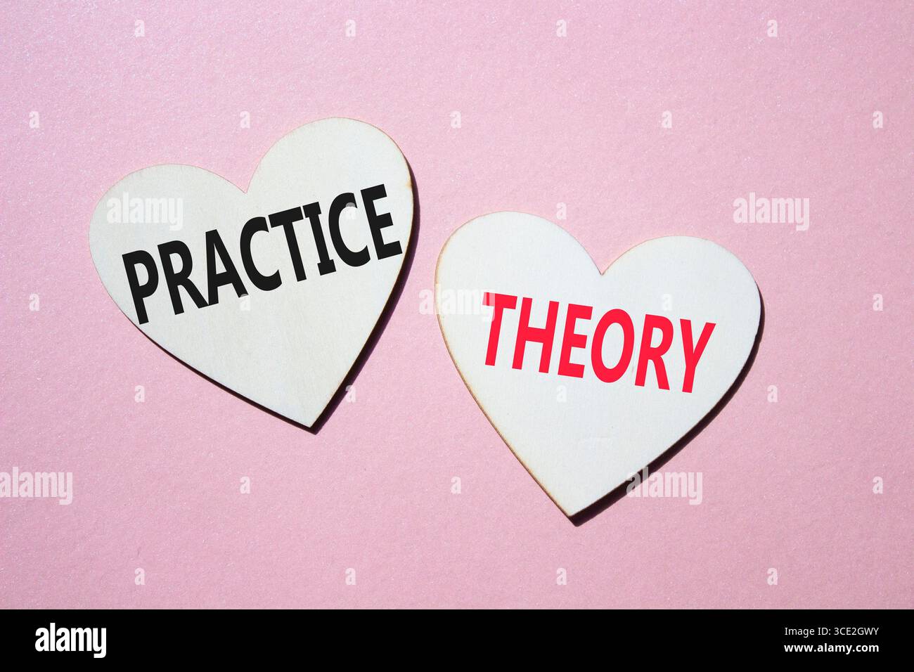 Theorie- oder Praxissymbol. Konzeptwort Theorie oder Praxis auf hölzernen Herzen. Schöner rosafarbener Hintergrund. Business and Theory oder Practice Concept. Kopieren Stockfoto