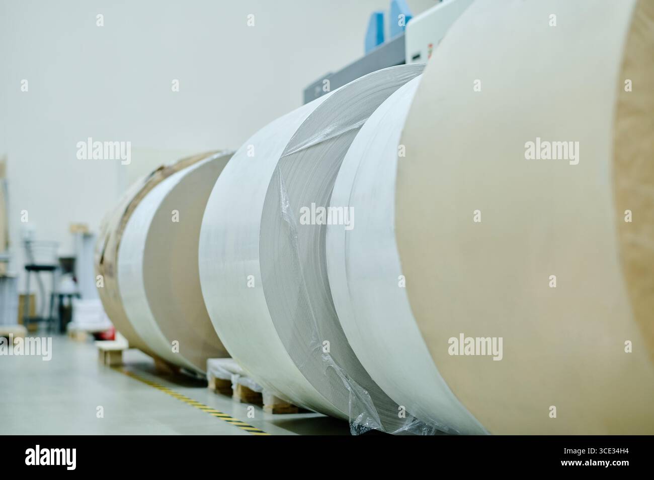 Keine Leute haben riesige Papierrollen in einem modernen Druckereilager geschossen Stockfoto