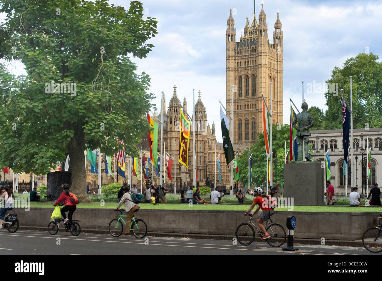 Radfahrer fahren an den Houses of Parliament in London vorbei. Fahnen der Commonwealth-Länder fliegen vor dem Gebäude. Stockfoto