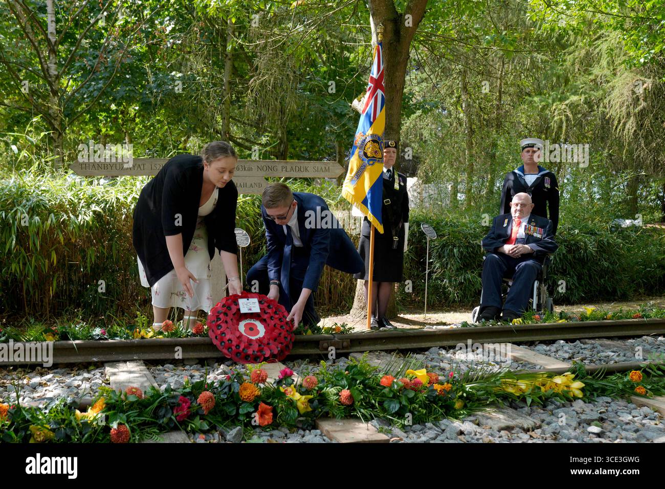 Veteran des Zweiten Weltkriegs Alfred Conway (rechts) aus Lincolnshire, der bei der Royal Navy diente, beobachtet, wie seine Urenkel Sarah-Jayne Carpenter (links) und James Carpenter (zweiter links) während eines Empfangs für VJ-Veteranen und ihre Familien im Aspect Building einen Kranz auf dem Denkmal der Burma Thailand Railway im 80 National Memorial Arboretum in Alreaffordshire legen. Bilddatum: Freitag, 15. August 2025. Stockfoto