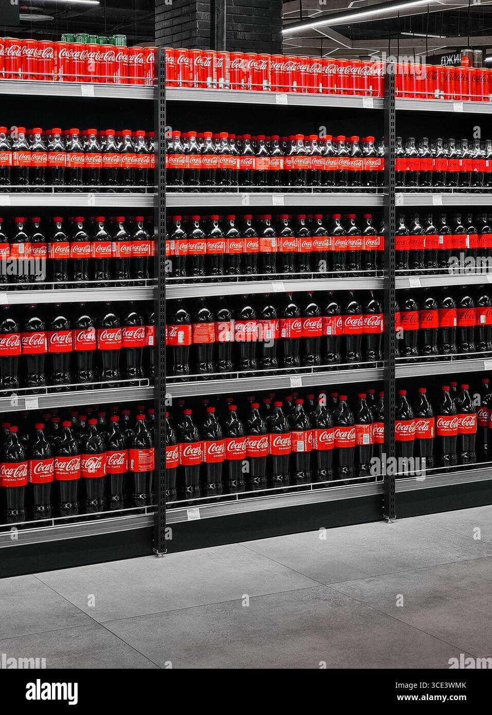 Reihen Cola-Flaschen zum Verkauf auf Racks. Sehen Sie sich die überfüllten Regale voller unterschiedlich großer Coca Cola Flaschen im modernen Supermarkt an. Stockfoto