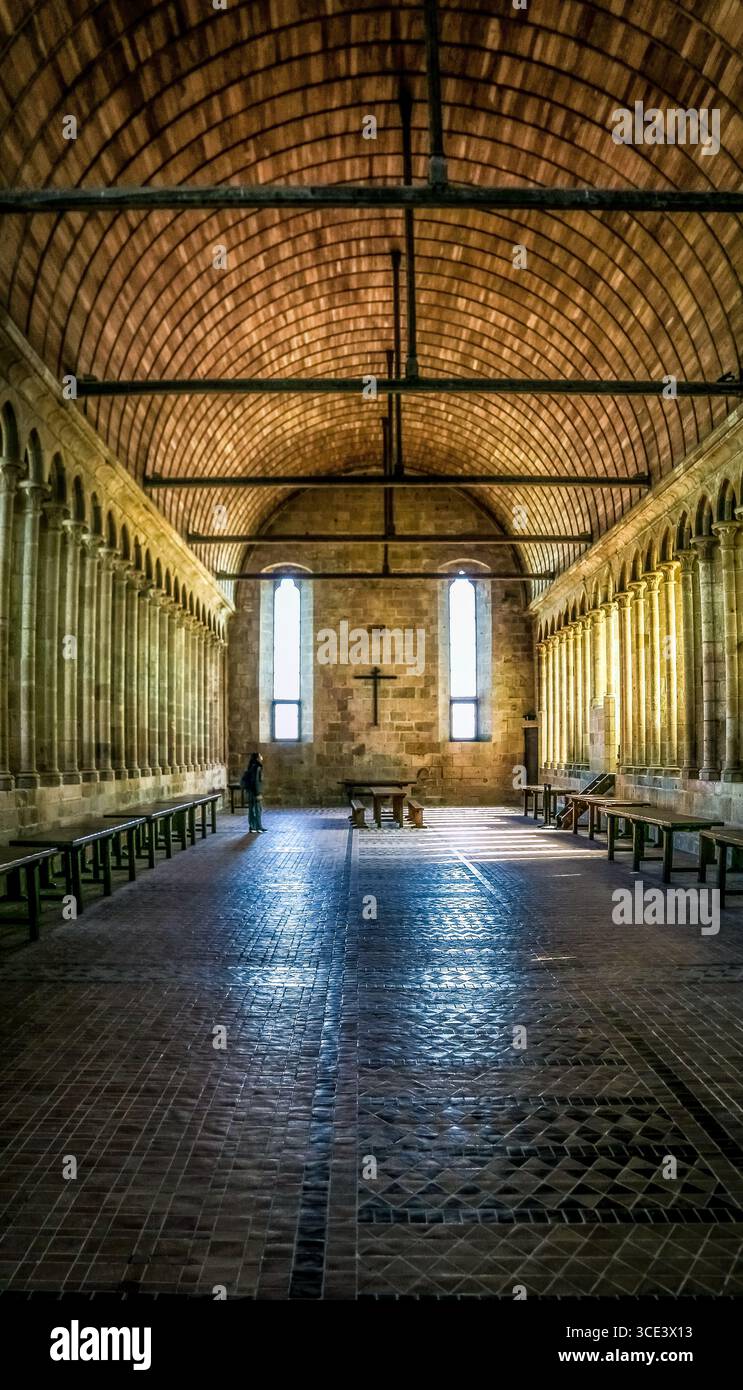 Beeindruckender Blick auf das Refektorium in der berühmten Abtei Mont-Saint-Michel. Lange, schmale Proportionen mit großer Holzdachkonstruktion und gefiltertem Licht... Stockfoto