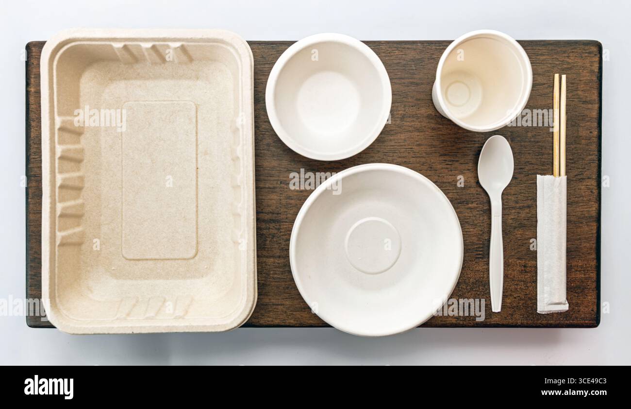 Ein umweltfreundliches Einweggeschirr-Set mit Tablett, Schüsseln, Becher, Löffel und Essstäbchen auf Holzoberfläche fördert Nachhaltigkeit Stockfoto