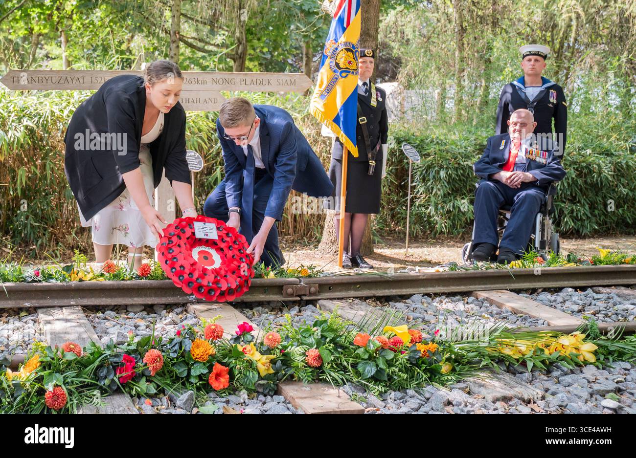 Veteran des Zweiten Weltkriegs Alfred Conway (rechts) aus Lincolnshire, der bei der Royal Navy diente, beobachtet, wie seine Urenkel Sarah-Jayne Carpenter (links) und James Carpenter (zweiter links) während eines Empfangs für VJ-Veteranen und ihre Familien im Aspect Building einen Kranz auf dem Denkmal der Burma Thailand Railway im 80 National Memorial Arboretum in Alreaffordshire legen. Bilddatum: Freitag, 15. August 2025. Stockfoto