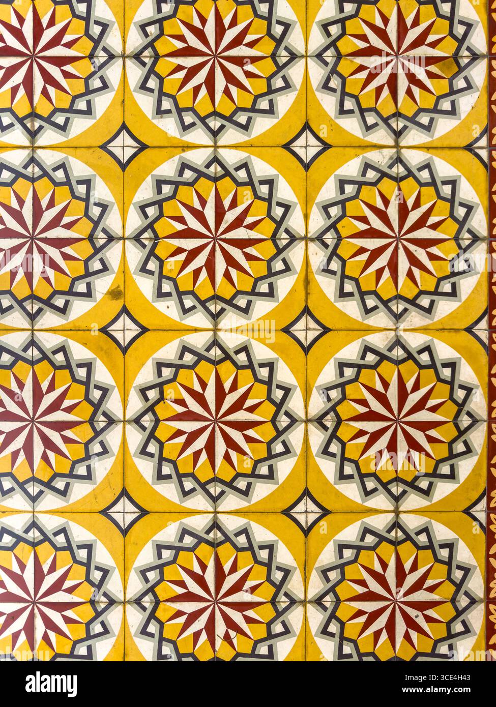 Farbenfrohes geometrisches Fliesenmuster mit Sternmotiven in Gelb-, Rot- und Grautönen für ein lebendiges, symmetrisches Design. Stockfoto