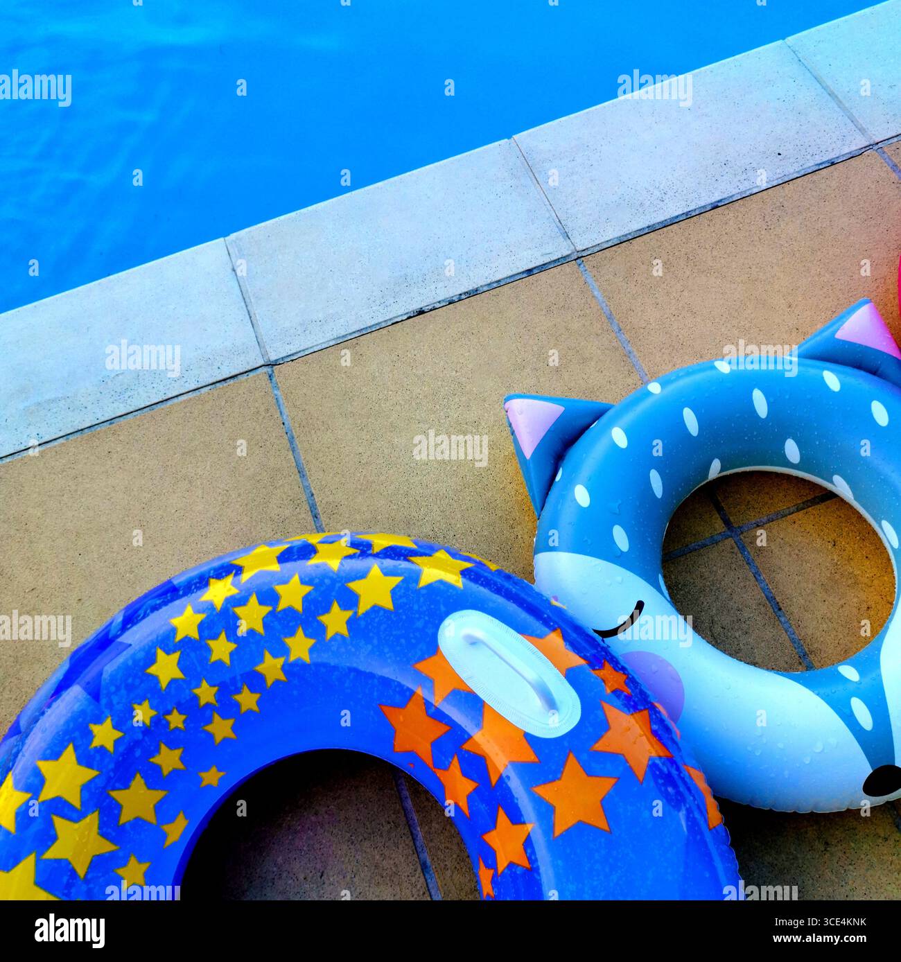 Zwei skurrile Schwimmbecken liegen neben einem glitzernden blauen Swimmingpool, was eine fröhliche Atmosphäre schafft. Frankreich - Smartphone-aufgenommenes Stockfoto