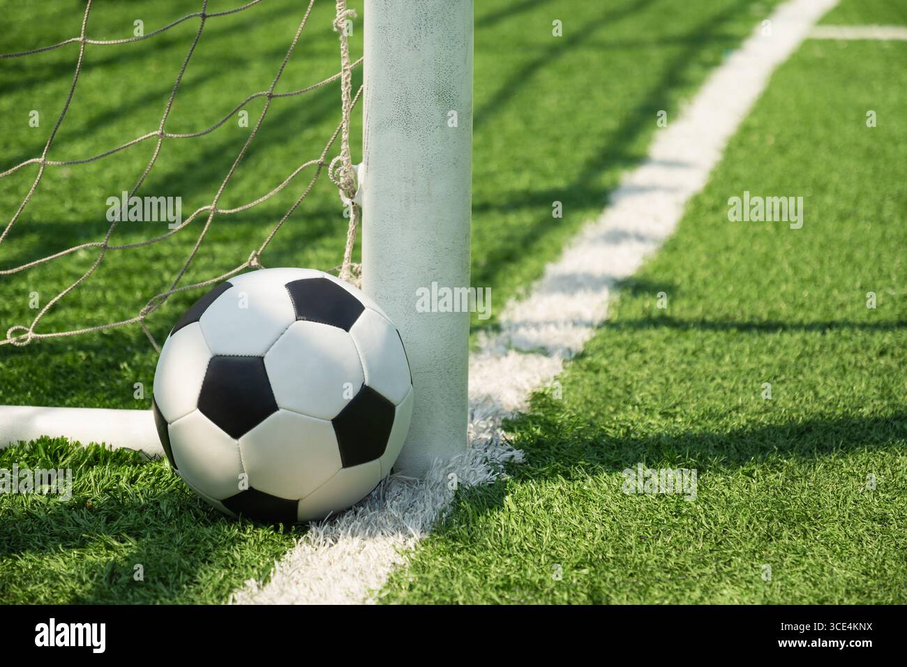 Fußball in der Nähe von Torpfosten auf dem grünen Rasenfeld nach dem Spiel im Stadion. Hintergrund des Fußballstadions. Sommersport, Teamspiele. Stockfoto