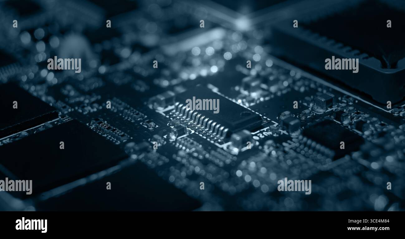 Das komplizierte Design einer Leiterplatte wird hervorgehoben und zeigt verschiedene elektronische Komponenten und Anschlüsse bei schlechten Lichtverhältnissen. Stockfoto