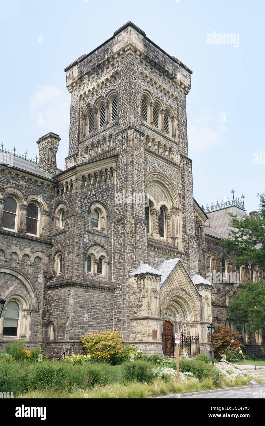 Historischer Steinturm und bogenförmiger Eingang des University College mit kunstvollen Details und landschaftlich gestaltetem Grün. Stockfoto