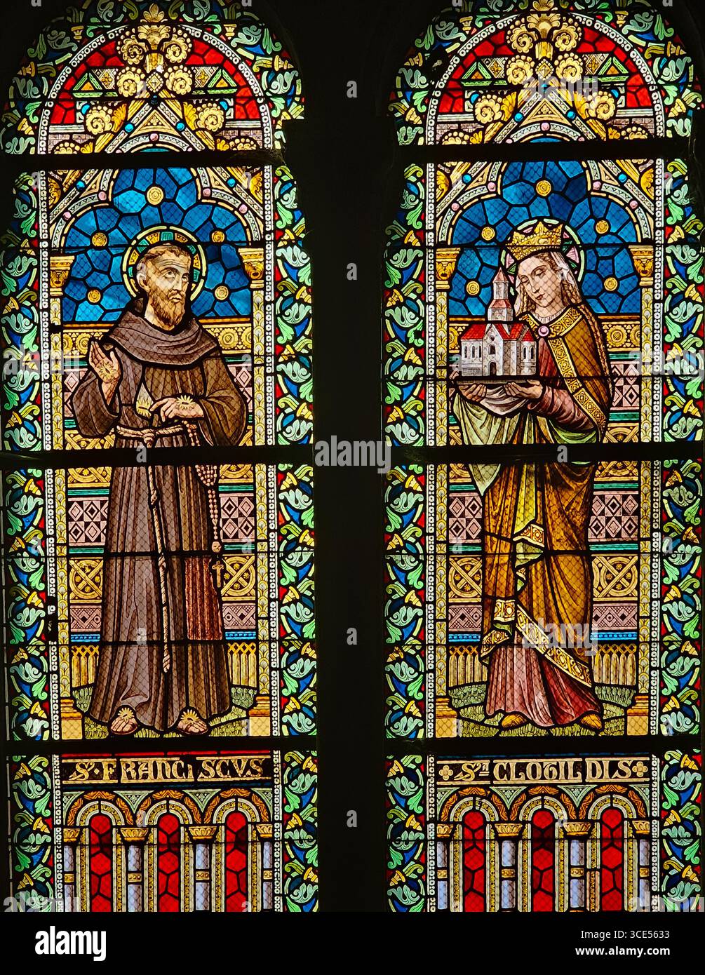 Rochefort, Belgien - 23. Juli 2025: Buntglasfenster, das den Heiligen Franziskus mit einem Kruzifix und die Heilige Clotilde mit einem Kirchenmodell zeigt Stockfoto