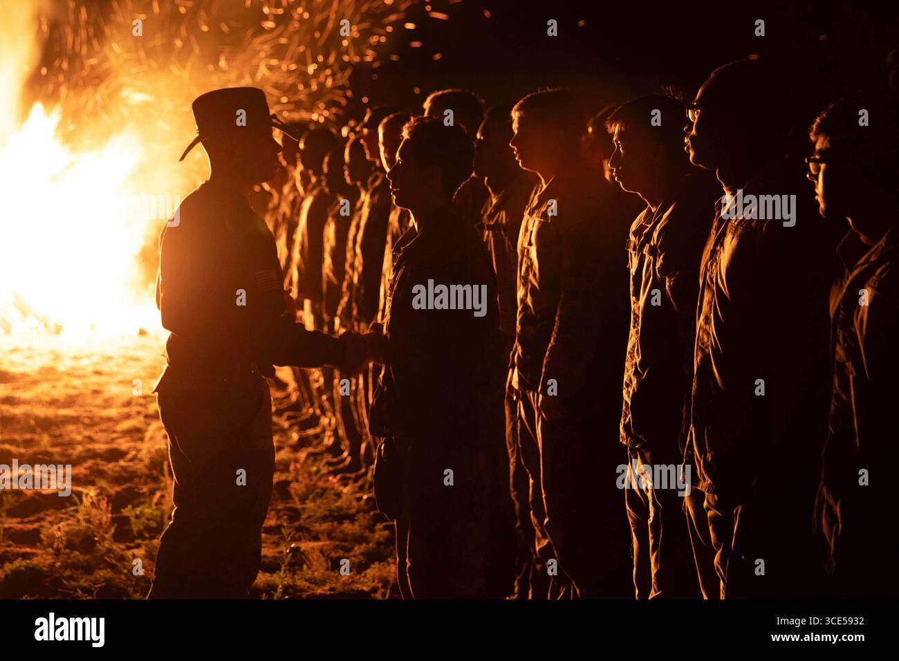 Estland. August 2025. Befehlshaber Hauptabteilung. Jose Padilla, Sergeant Major der 5. Geschwader, 7. Kavallerie-Regiment, 1. Panzerbrigade Combat Team, 3. Infanterie-Division, gratuliert einem Soldaten beim Lagerfeuer, das den Abschluss der Spur-Fahrt im August feiert. 11, 2025, in Camp Reedo, Estland. Der Spur Ride ist eine altehrwürdige Tradition, die durch Generationen von Kavallerie-Einheiten der US-Armee weitergegeben wurde, wo Soldaten eine rigorose Reihe von Veranstaltungen absolvieren, um sich das Recht zu verdienen, die silbernen Sporen zu tragen. Die Einführung in den Orden der Spur bedeutet Bereitschaft und Kompetenz als Kavallerie-Soldat. (C Stockfoto