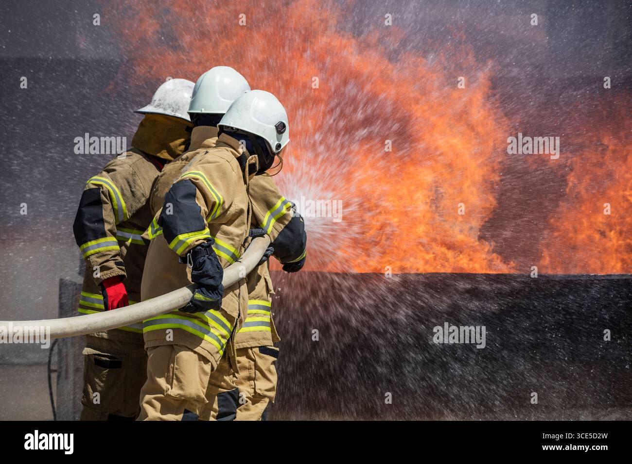 Feuerwehrmänner, die auf einen Gebäudebrand reagieren, arbeiten gemeinsam mit Notfallausrüstung und Schutzausrüstung, um die Flammen zu kontrollieren und Leben und Eigentum zu schützen Stockfoto