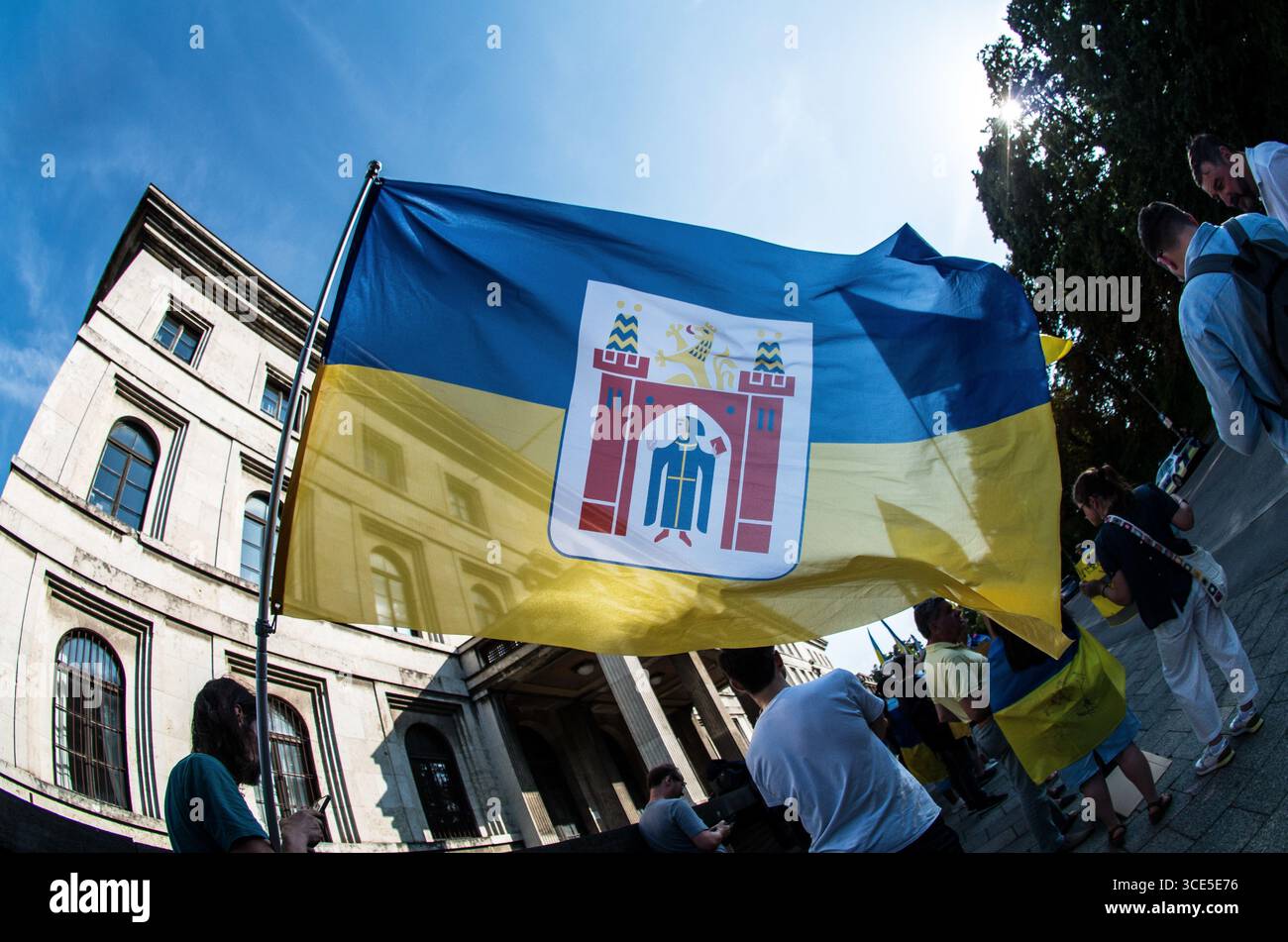 München, Bayern, Deutschland. August 2025. Die Flaggen von München und der Ukraine verschmolzen und symbolisieren die Unterstützung. Zeitgleich mit dem Gipfel von Alaska 2025 zwischen Donald Trump und dem russischen Wladimir Putin warnten Ukrainer und Deutsche in München am Ort des Münchner Abkommens von 1938 die westliche Allianz vor einem gefährlichen Beschwichtigungsszenario, ähnlich dem, als die Weltmächte Hitler erlaubten, das Sudetenland anzunektieren, was letztlich den Zweiten Weltkrieg nicht verhinderte. Andere sprachen von Jalta 1945, als Putin und Trump darüber diskutieren, das Land der Ukraine ohne die Anwesenheit von Zelenskyj zu teilen. Historiker und Analys Stockfoto