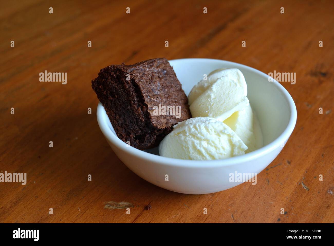 Ein Nachtisch aus einem reichhaltigen Schokoladenbrownie mit zwei Kugeln Vanilleeis in einer weißen Schüssel 1 Stockfoto