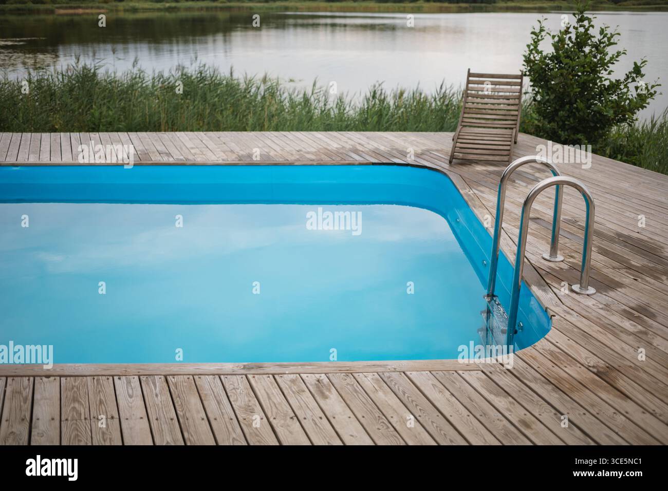 Nahaufnahme einer hölzernen Sonnenliege am Pool neben einem See Stockfoto