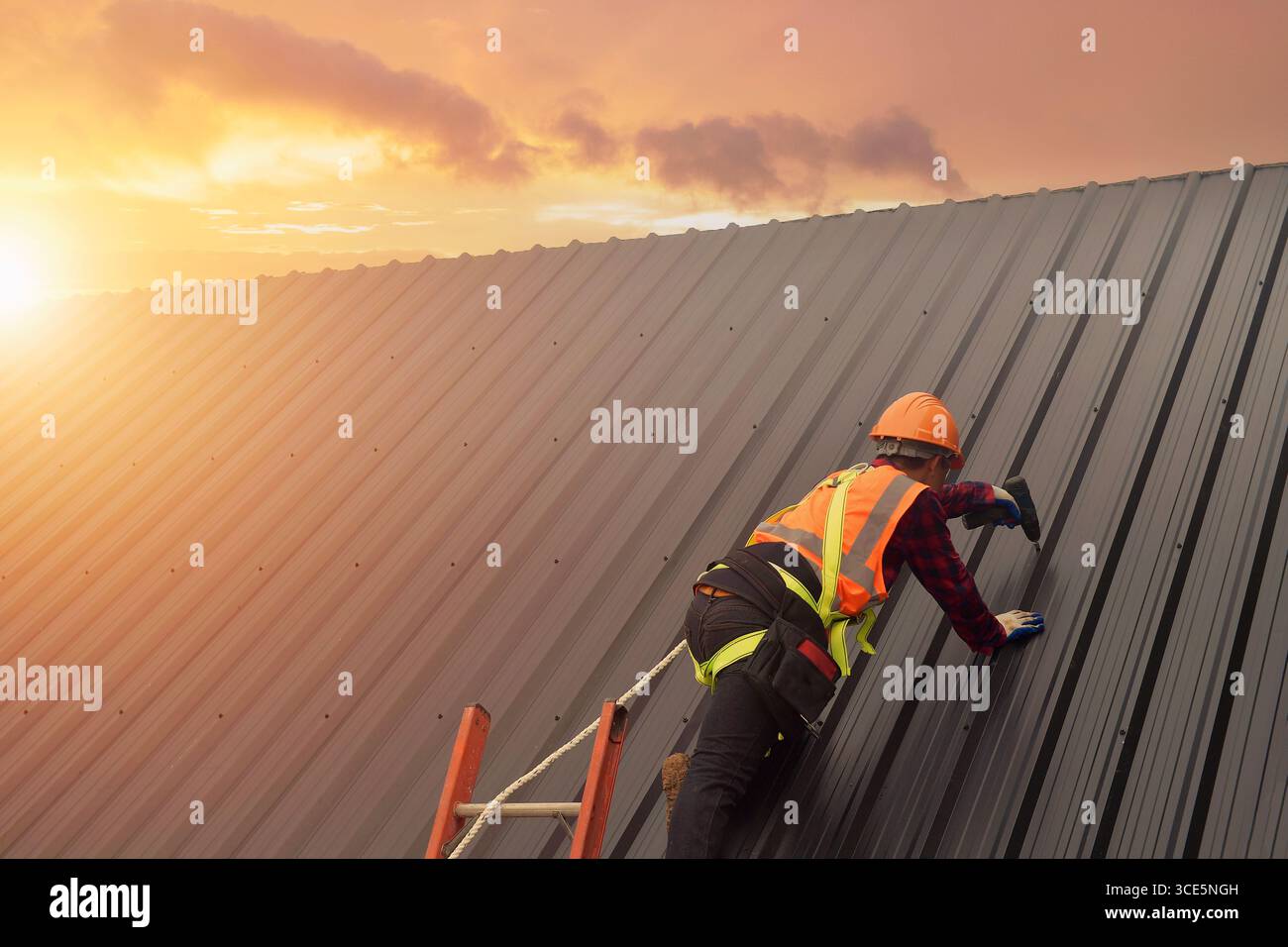 Rückansicht eines Dachdeckers in Arbeitsschutzkleidung, der mit einem Bohrer Metallbleche auf einem Dach installiert, Thailand Stockfoto