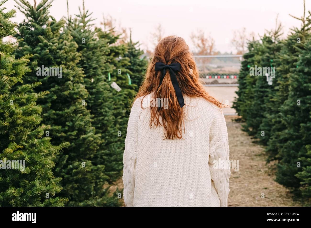 Frau mit rotem Haar und schwarzer Schleife auf einer Weihnachtsbaumfarm Stockfoto
