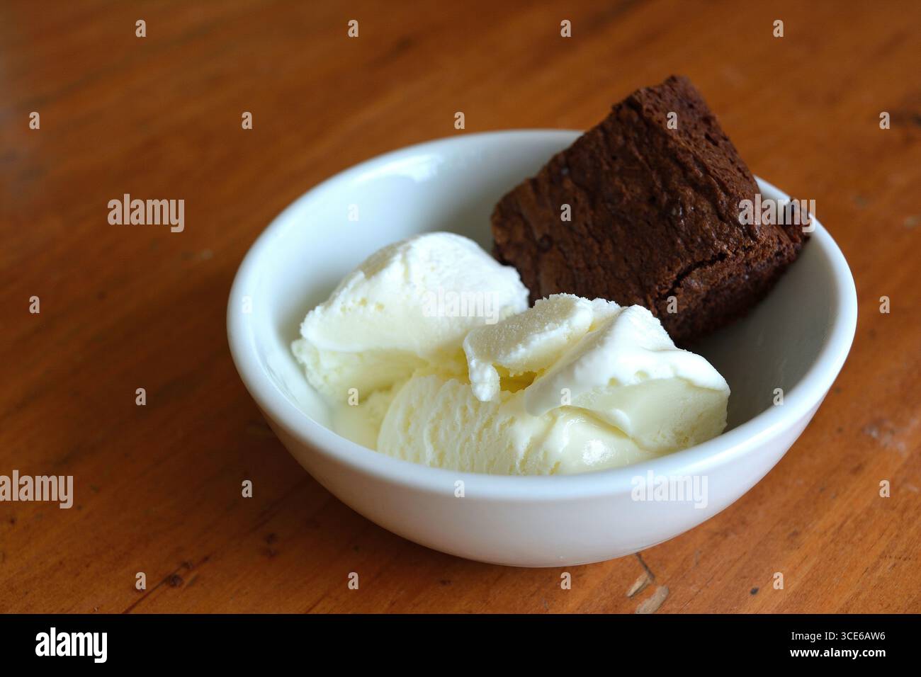 Ein Nachtisch aus einem reichhaltigen Schokoladenbrownie mit zwei Kugeln Vanilleeis in einer weißen Schüssel 3 Stockfoto