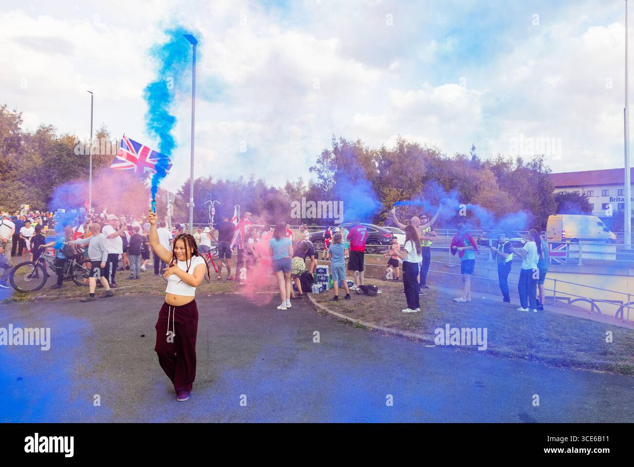 Leeds, Großbritannien. AUGUST 2025. Junge Person hält bunte Fackeln, als sich in der vierten Woche die gegnerischen Pro- und Anti-Migrant-Demonstranten am Straßenrand in der Nähe des Britannia Hotels in Seacroft, Leeds, versammelten. Die Demonstranten der 'Stand Up Leeds' zündeten mehrere Fackeln an, und drei Gegenprotestierende wurden verhaftet, nachdem es zwischen Aktivisten und Polizei zu Streitigkeiten gekommen war. Credit Milo Chandler/Alamy Live News Stockfoto