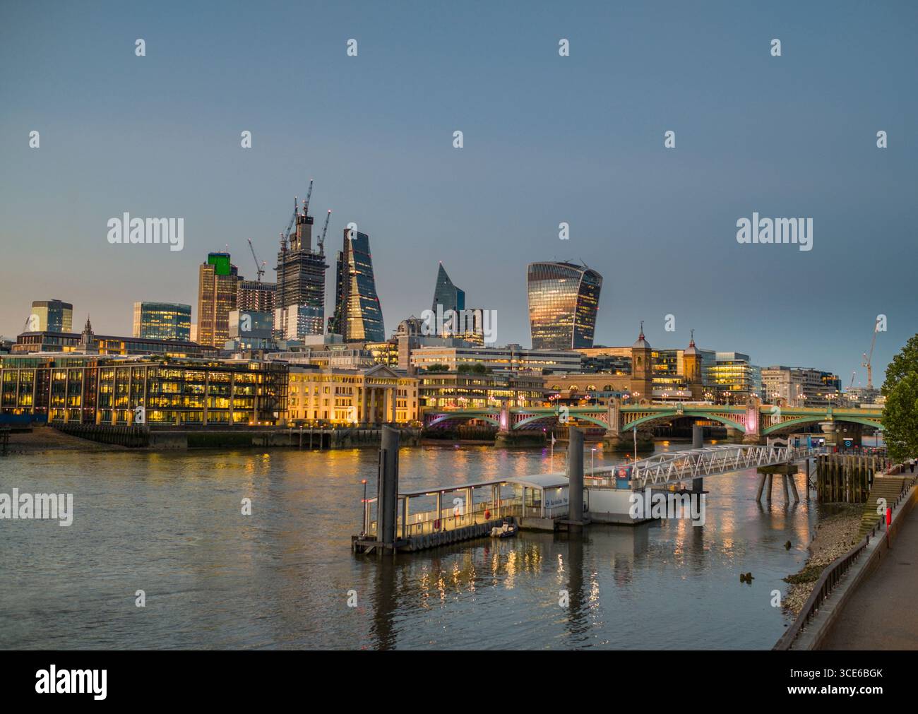 Skyline von London in der Dämmerung mit der Bankside Ferry Terminal auf der Themse im Vordergrund, von der South Bank, Southwark, London, England, U Stockfoto