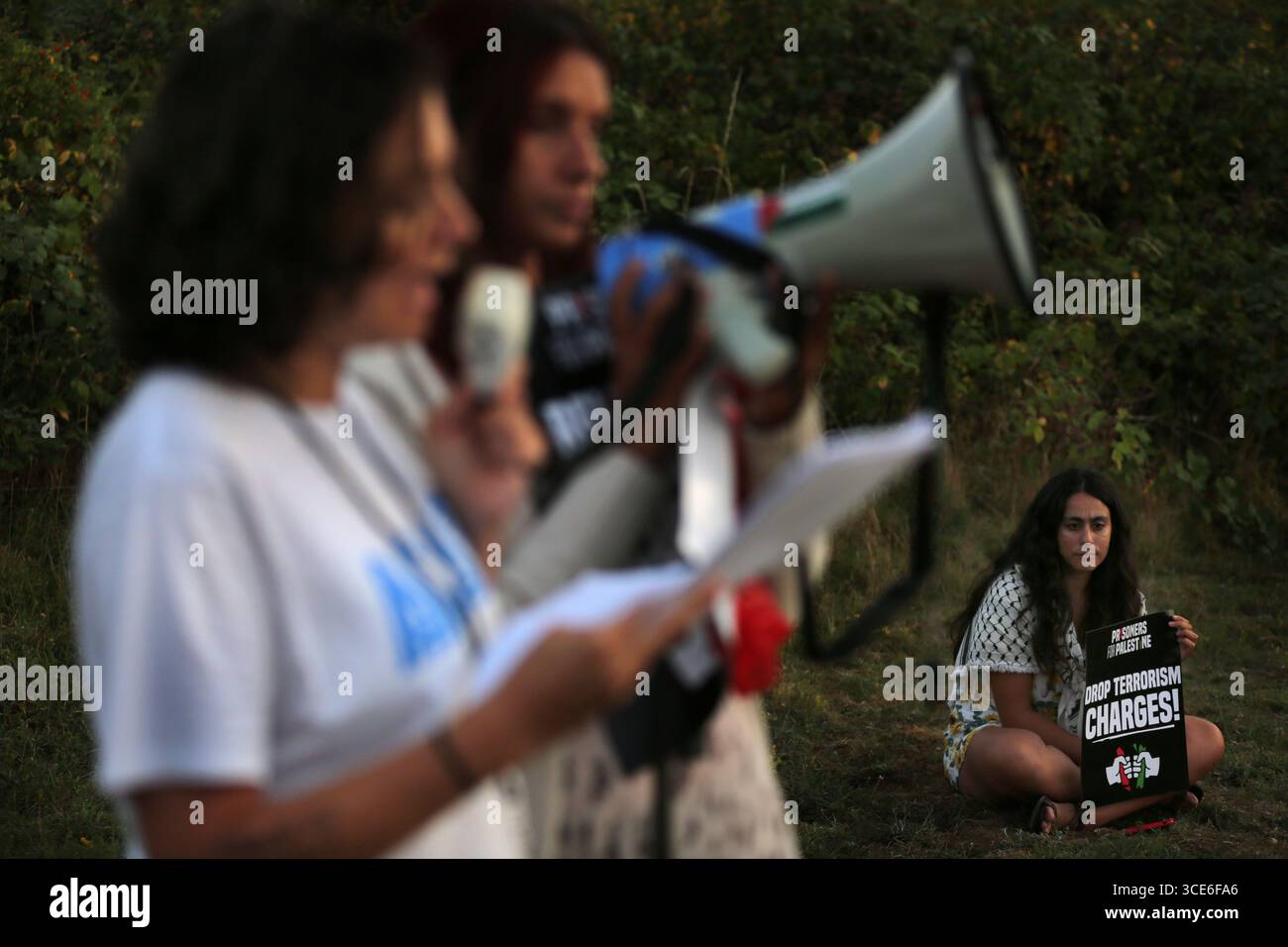 Ein Demonstrant spricht durch ein Megaphon während eines Prisoners4Palestine Starts bei einer Kundgebung vor HMP Peterborough. Prisoners4Palestine ist eine kollektive Anstrengung, um sich denjenigen innerhalb des Gefängnissystems anzuschließen, die Maßnahmen gegen Völkermord, Imperialismus und Unterdrückung ergriffen haben und jetzt dafür brutal bestraft werden. Das Gefängnis beherbergt drei der Filton24-Gefangenen, einer befindet sich derzeit im Hungerstreik. Die Kundgebung ist ein Jahr her, seit die Filton-Gefangenen in Untersuchungshaft genommen wurden und ehrt den Hungerstreik der palästinensischen Gefangenen von 2004. Sie verlangen, dass Elbit Systems heruntergefahren wird, freie Assoziation Stockfoto