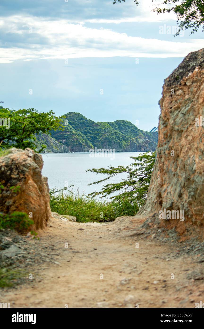 Ein malerischer Pfad führt zum Cabo San Juan Strand im Tayrona Park, Santa Marta, Kolumbien, mit üppigem Grün und ruhigem Wasser. Stockfoto