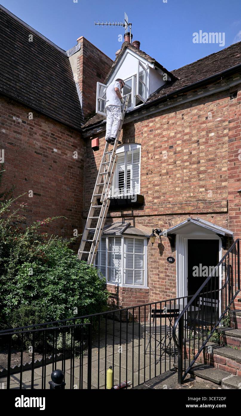 Hausmaler draußen arbeitet eine Leiter hoch. England, Großbritannien Stockfoto
