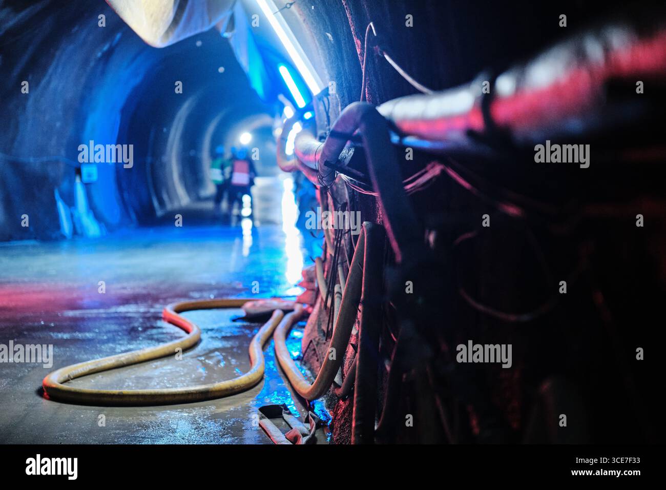Wasserkraftwassertunnel mit Schläuchen und Industriebeleuchtung Stockfoto
