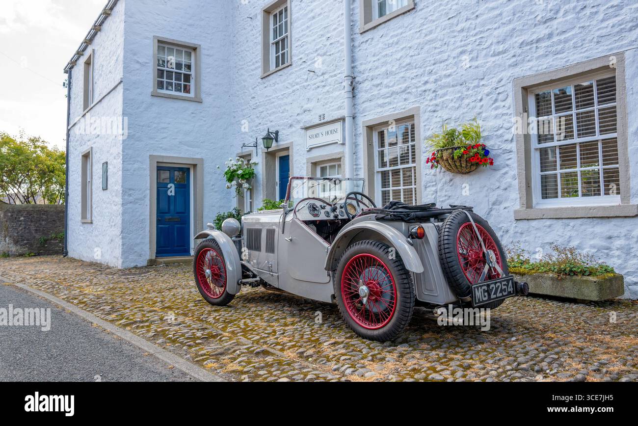 Vollständig restaurierte MG J2 Midget in Hellgrau gestrichen und auf einem Kopfsteinpflaster vor einem weiß gemalten Steinhaus stehend. Stockfoto