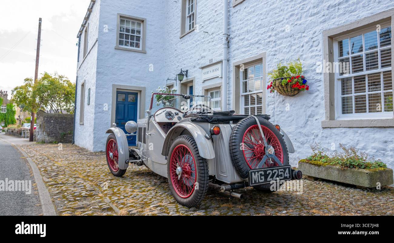 Vollständig restaurierte MG J2 Midget in Hellgrau gestrichen und auf einem Kopfsteinpflaster vor einem weiß gemalten Steinhaus stehend. Stockfoto