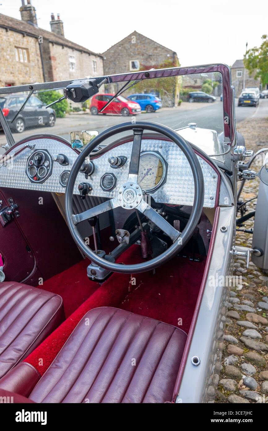 Vollständig restaurierte MG J2 Midget in Hellgrau gestrichen und auf einem Kopfsteinpflaster vor einem weiß gemalten Steinhaus stehend. Stockfoto
