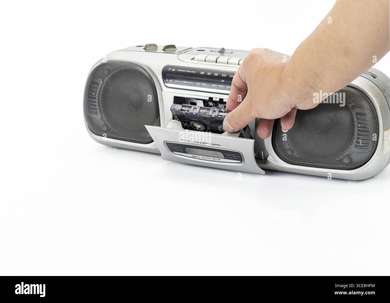 Eine Hand, die eine Kassette in einen tragbaren Vintage-Stereo-Player einführt, Retro-Audiogeräte, nostalgische Stimmung, isoliert auf weißem Hintergrund, Nahaufnahme Stockfoto