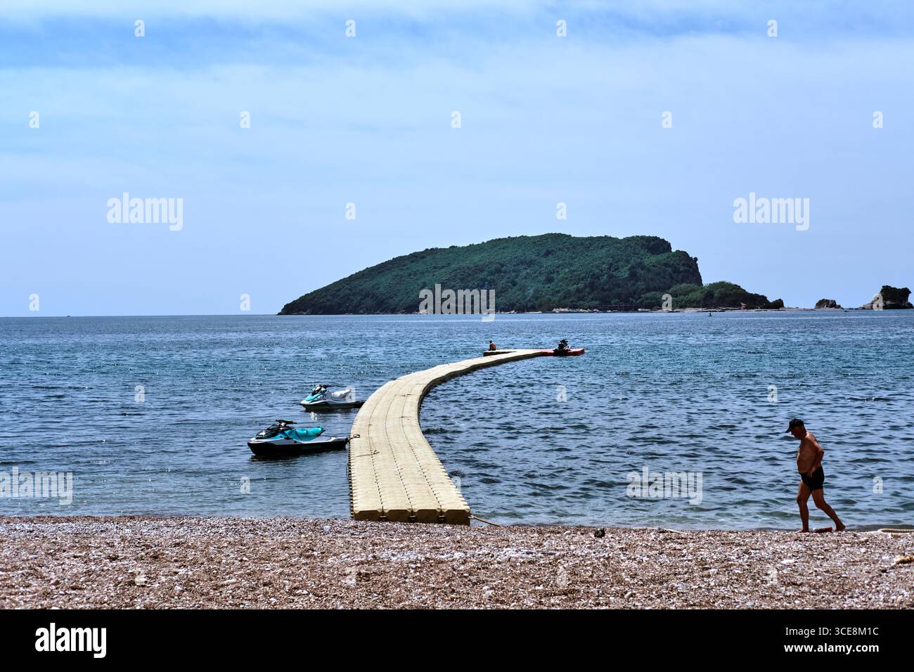 Mann in Badehosen, der an einem temporären Plastikdock am Budva Beach, Montenegro an der budva riviera vorbeiläuft Stockfoto