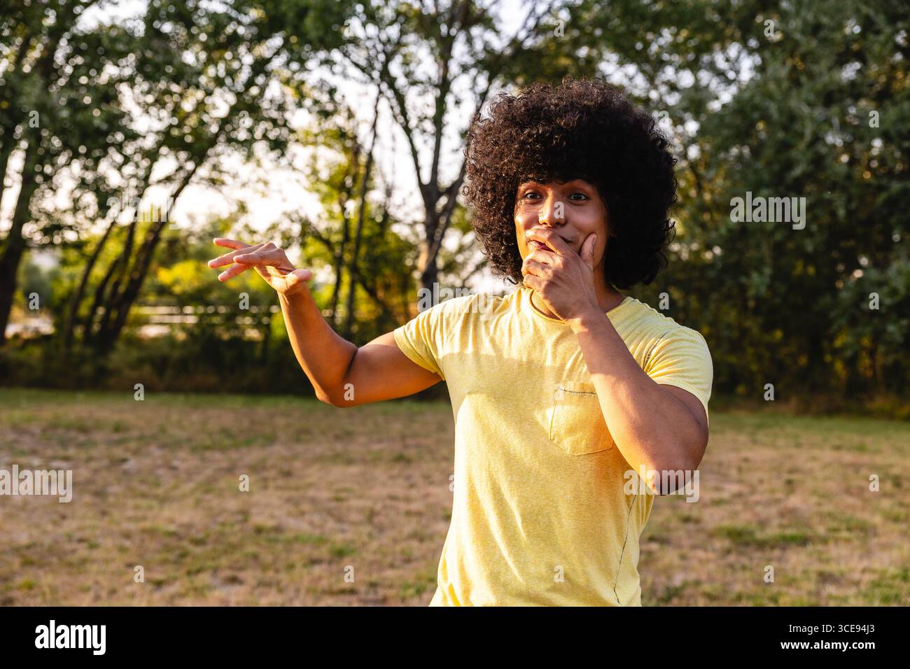 Junger Mann, der überrascht ist und im Park den Mund bedeckt Stockfoto