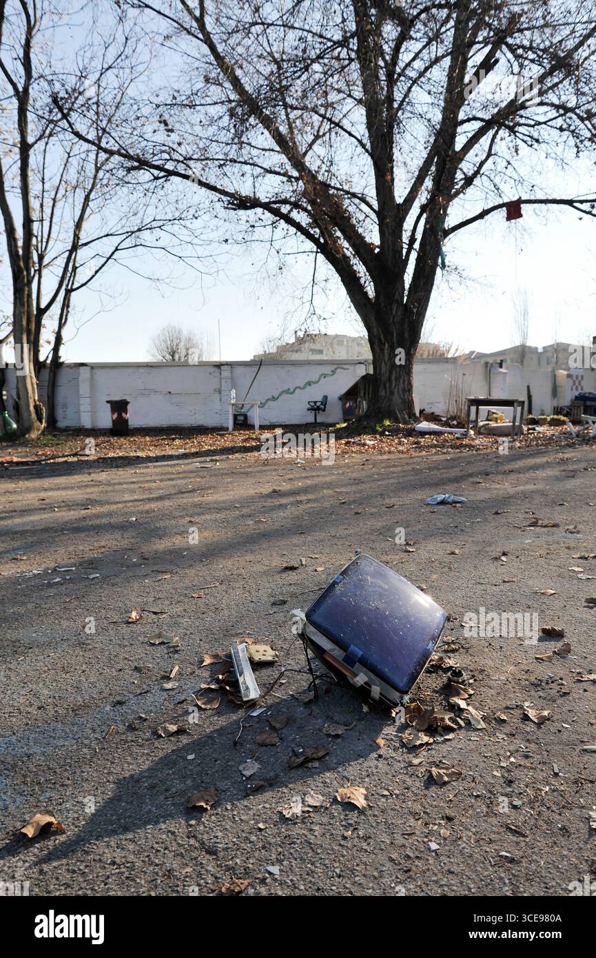 Kaputte CRT-Fernseher auf einem leeren Stadtgrundstück, umgeben von Trümmern und blattlosen Bäumen, verlassen. Ein symbolisches Bild technologischer Obsoleszenz, Zerfall A Stockfoto