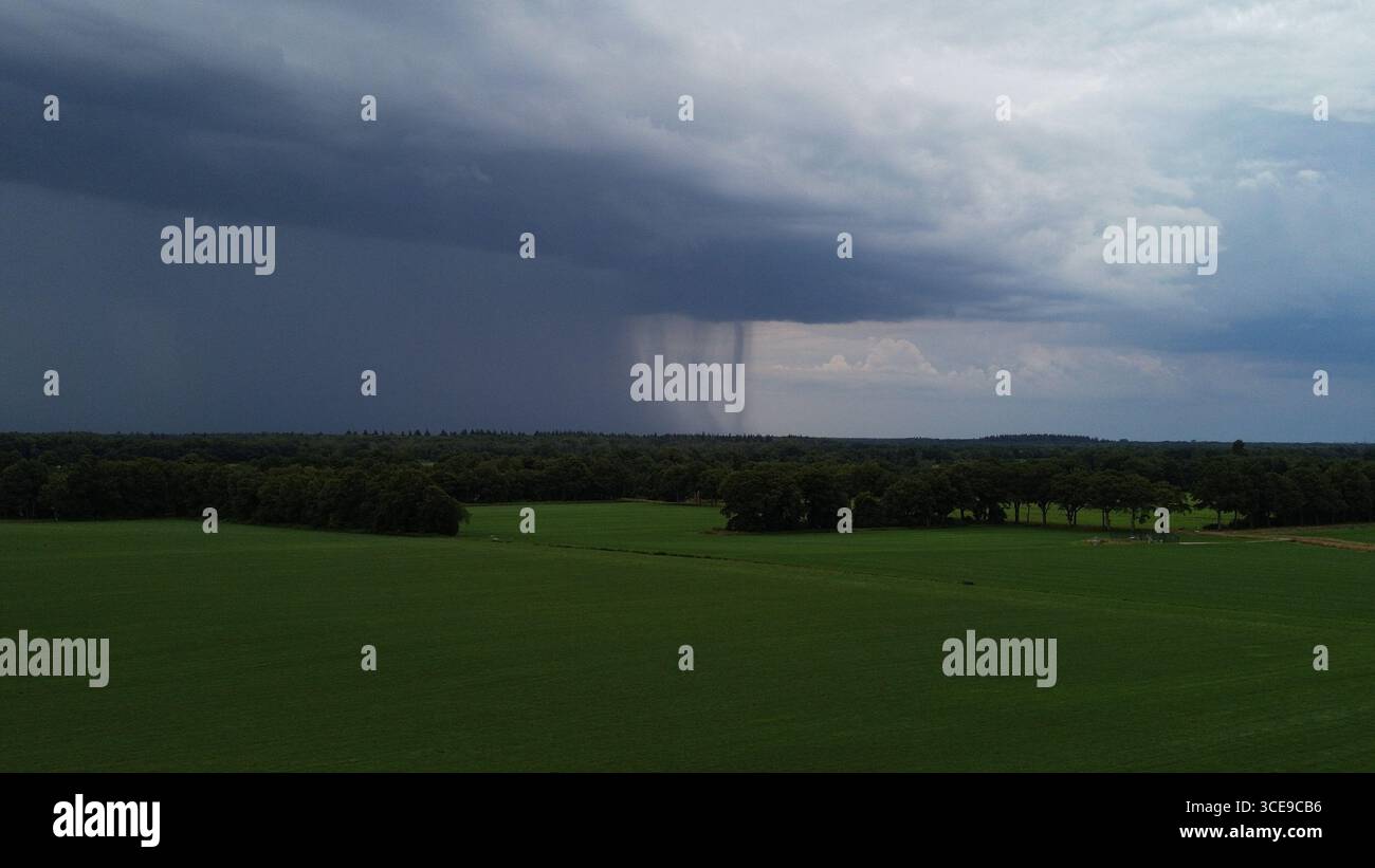 Aus den dunklen Wolken über den Wiesen fällt der Regen Stockfoto