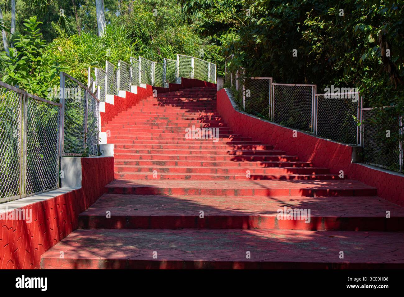 Leuchtend roter Fußweg mit geometrischen Steinmustern und Metallzaun im Dream Holiday Park Stockfoto