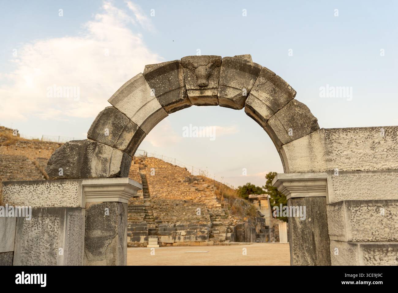 Antike römische Steinbogen am Eingang des Theaters von Philippi, mit geschnitztem Schlussstein und Arena im Hintergrund Stockfoto