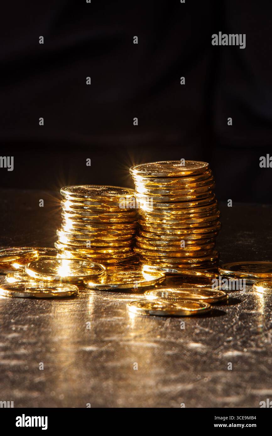 Zwei Stapel von Münzprägeanstalten, glänzenden kanadischen ein-Dollar-Loonie-Münzen in der Morgensonne mit dunklem Hintergrund für Kopierraum. Stockfoto