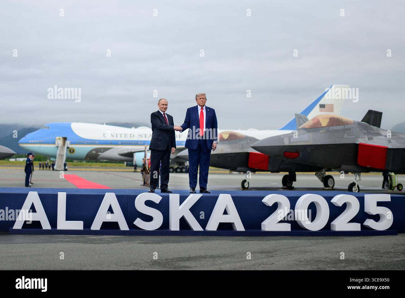 Präsident Donald J. Trump schüttelt dem russischen Präsidenten Wladimir Putin bei einem Gipfeltreffen auf der Joint Base Elmendorf–Richardson in Anchorage, Alaska, am 15. August 2025 die Hand. Das Treffen auf hoher Ebene konzentrierte sich auf Verhandlungen zur Beendigung des Krieges in der Ukraine, wobei im Hintergrund die Kampfflugzeuge der Air Force One und der US Air Force sichtbar waren. Bild mit freundlicher Genehmigung des Weißen Hauses Stockfoto
