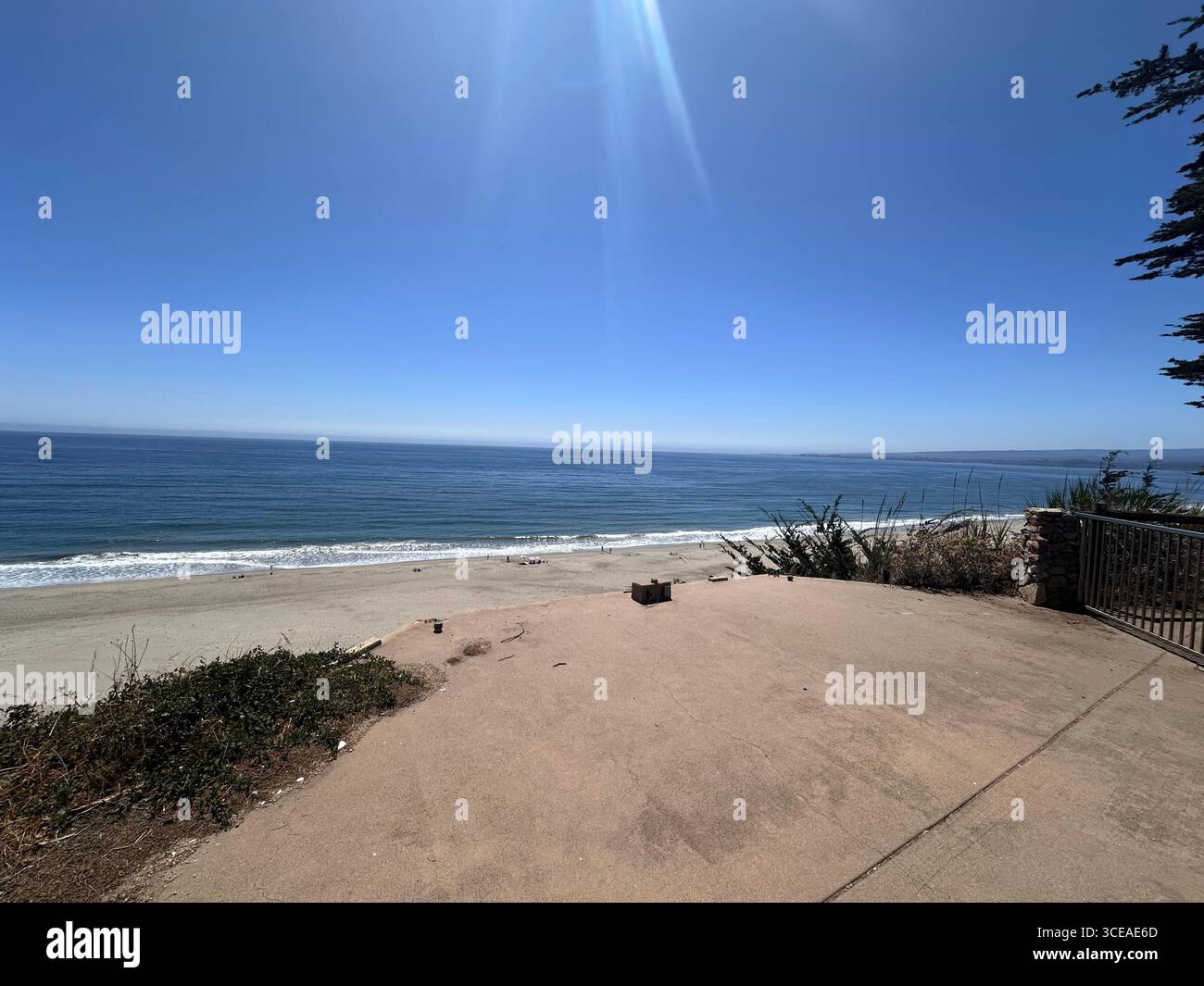Ein malerischer Blick auf die Küste von einer Klippe mit grasbewachsenen Dünen, Häusern am Meer und einem langen Sandstrand, der auf das ruhige blaue Wasser trifft - Smartphone-aufgenommenes Stockfoto
