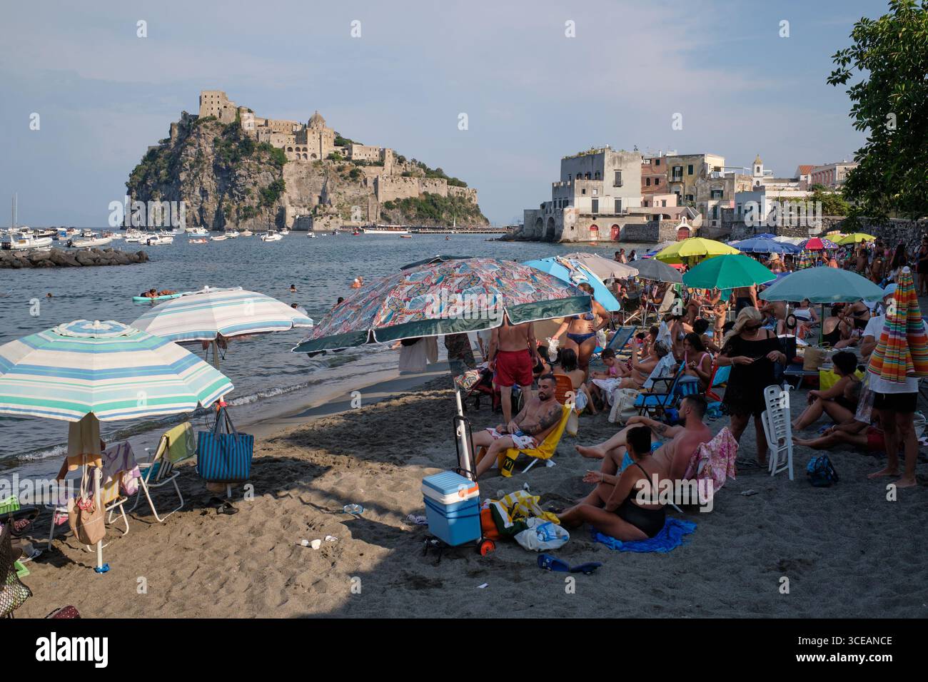 Die Menschen bleiben am Strand, da die aragonesische Burg am 16. August 2025 auf Ischia, einer Insel im Golf von Neapel, in Italien, zu sehen ist. Stockfoto