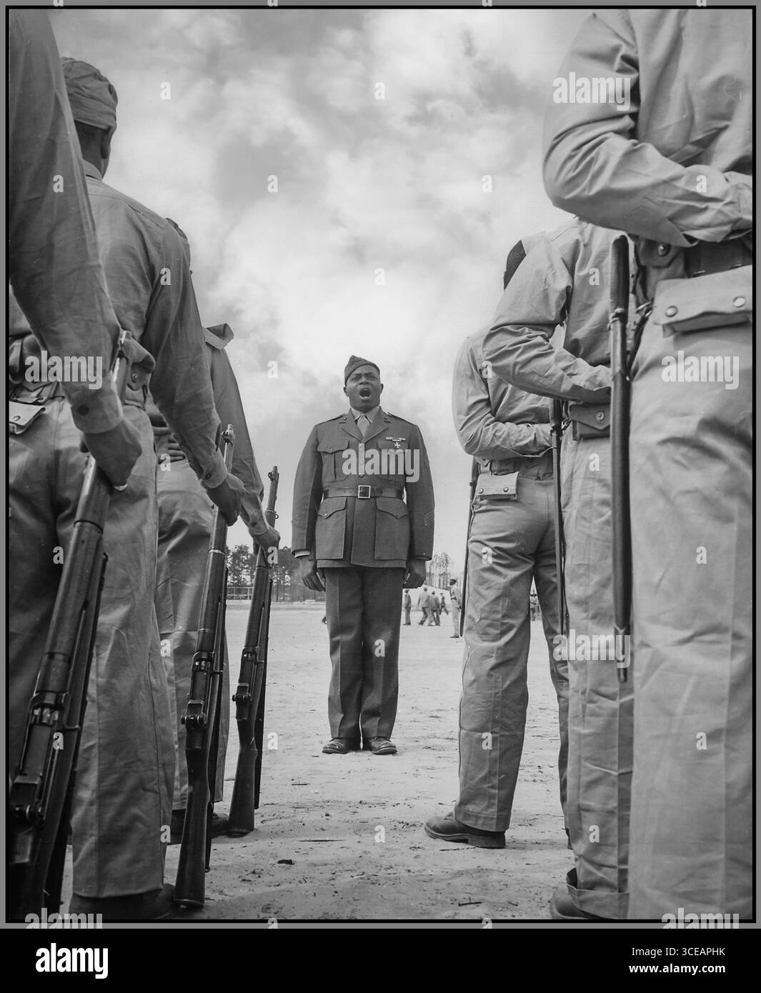 Propagandafoto des Zweiten Weltkriegs von einem Zug afroamerikanischer 'Boot Recruits' hören ihrem Bohrlehrer [Sgt. Gilbert Hubert Johnson] zu, dessen Aufgabe es ist, sie in fertige Marines zu verwandeln.', ca. 04/1943 Datum ca. April 1943 Stockfoto
