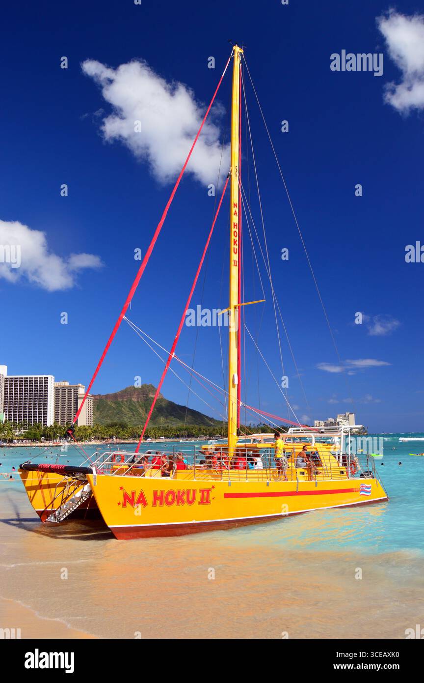 Ein gelber Katamaran fährt an der Küste von Waikiki Beach, Hawaii, und ist bereit, die nächste Gruppe von Passagieren auf ihr nächstes Abenteuer und ihre nächste Reise mitzunehmen Stockfoto