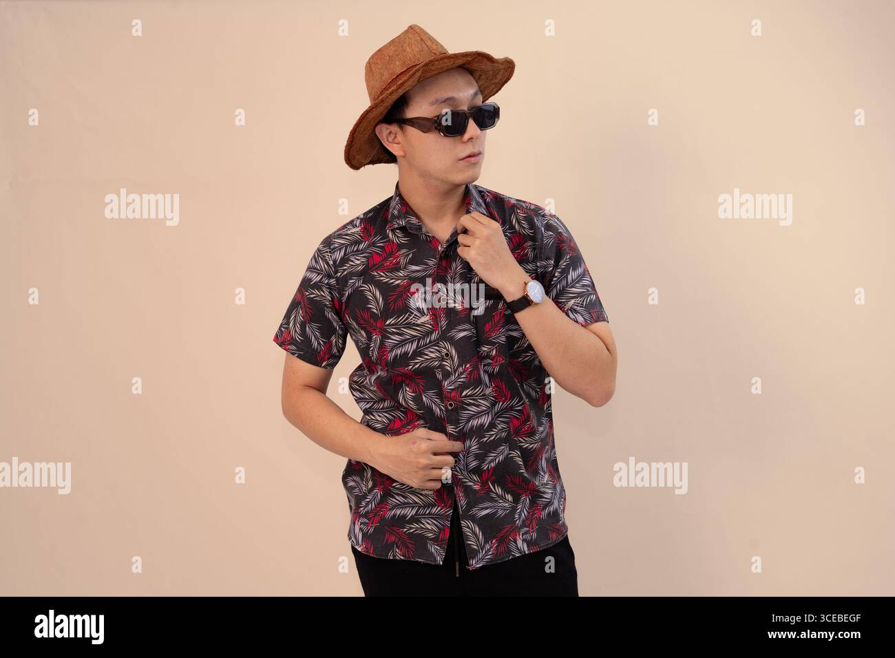 Stilvoller Mann posiert in tropischem Hemd, Sonnenbrille und Strohhut Mode lässig Stockfoto