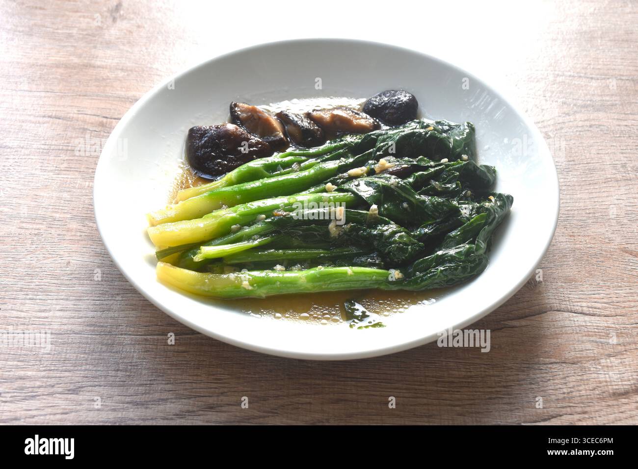Gebratene Kailaan Chinesischer Grünkohl und schwarzer Pilzdressing Austernsauce mit Knoblauch auf Teller Stockfoto