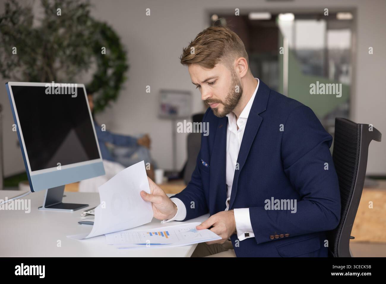 Fokussierter junger Geschäftsanalyst, der Vertriebsmarketing-Berichte überprüft Stockfoto